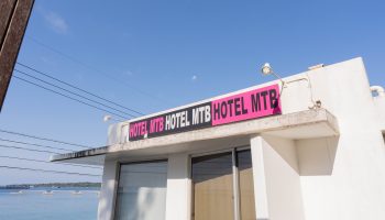 ホテル美らビーチ外観とピンクのサインボード
